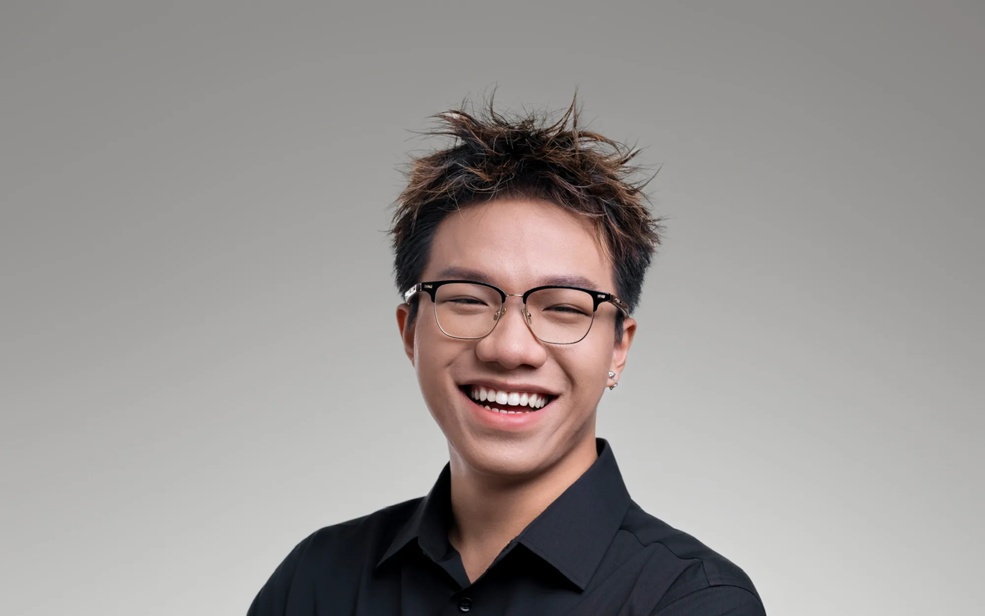 Austin Zhang, laughing, in a studio portrait against a pale grey ground.