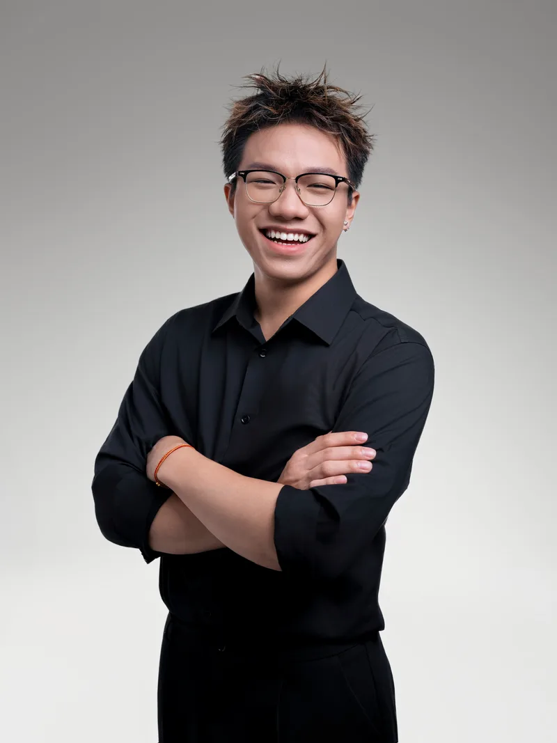 Austin Zhang, arms folded and laughing, in a studio portrait.